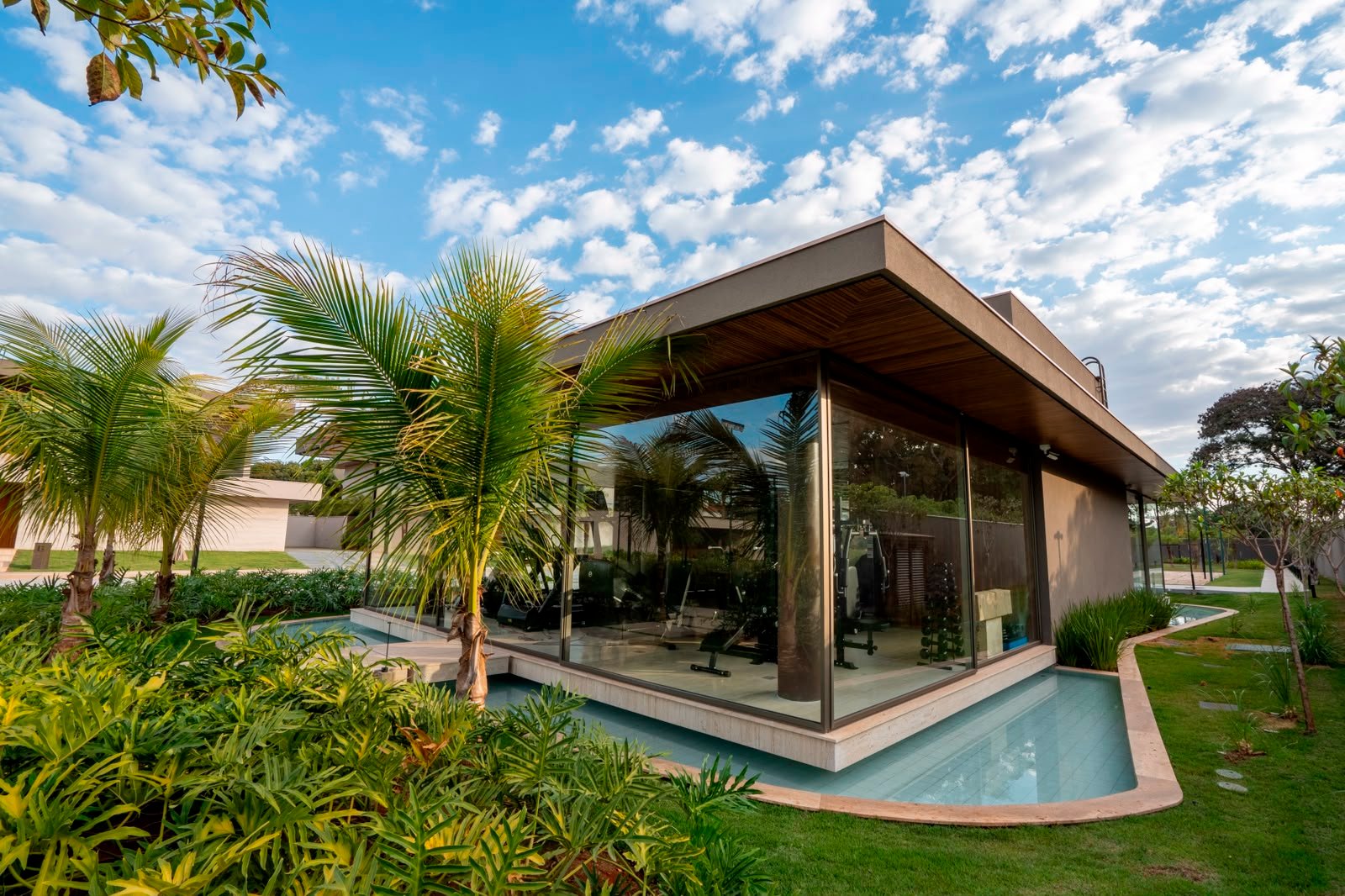 Pavilhão envidraçado entre o paisagismo da residência